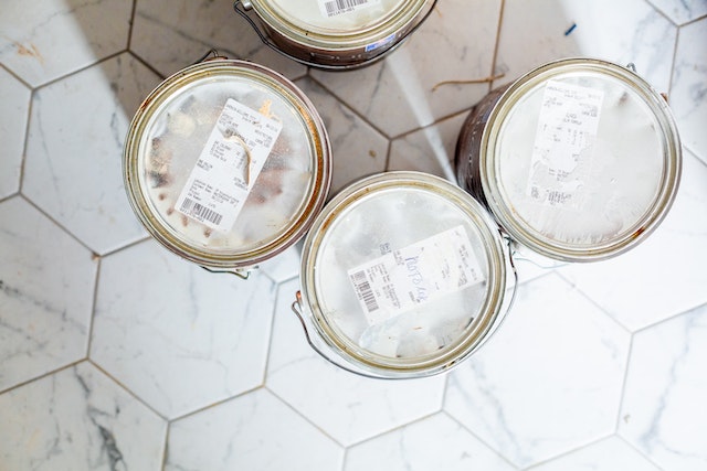 unopened paint cans on a white tile floor